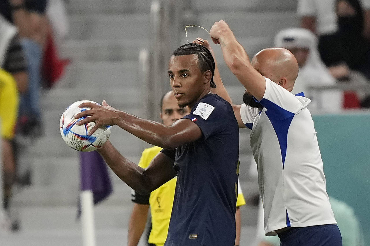An assistant coach takes of the necklace of France's Jules Kounde during the World Cup round of 16 ...