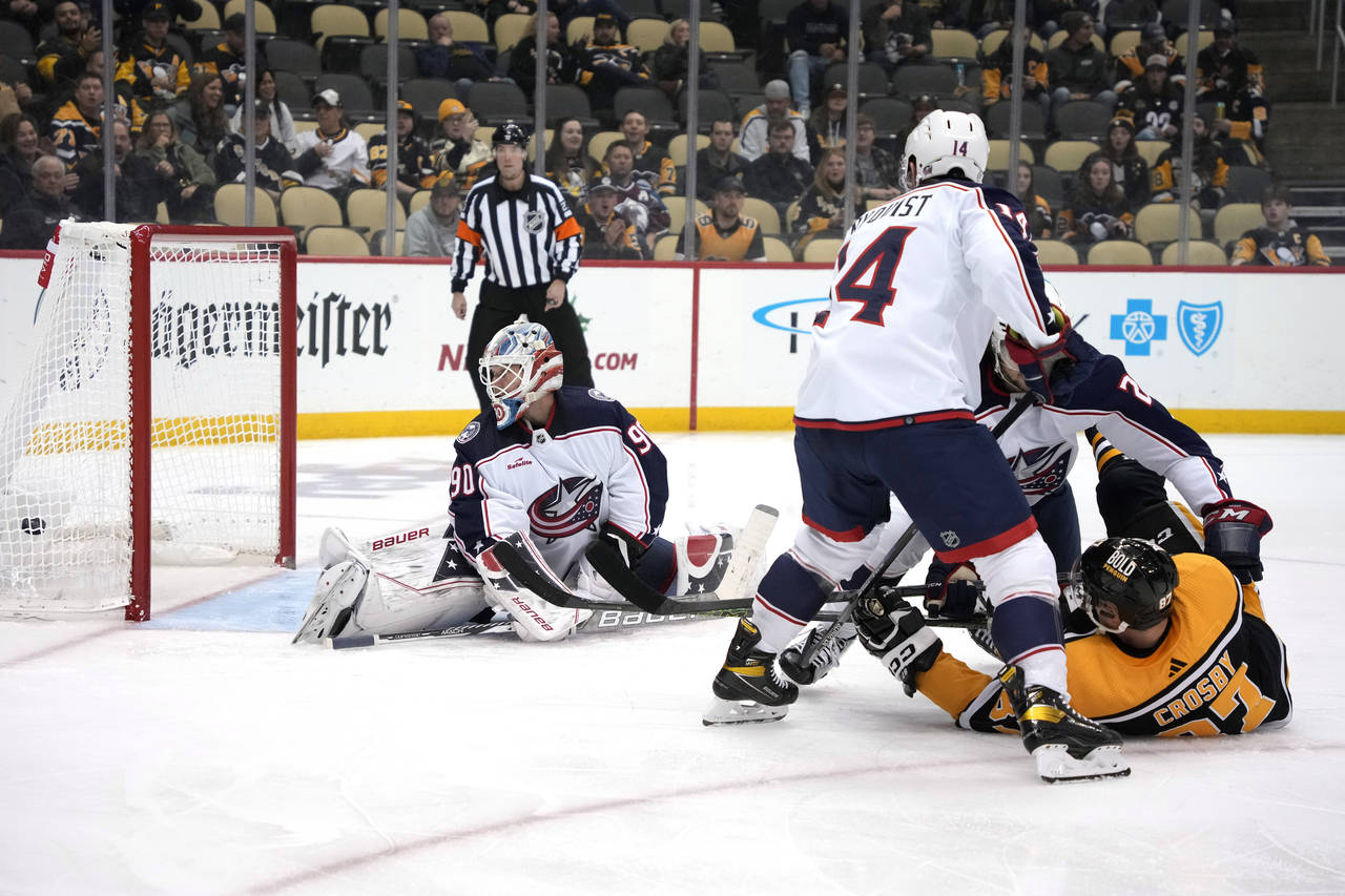 Pittsburgh Penguins' Sidney Crosby falls to the ice as he gets a shot past Columbus Blue Jackets go...