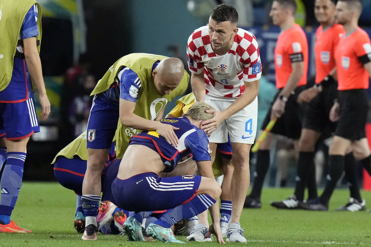 Japan's Takuma Asano, center, is comforted by Croatia's Ivan Perisic, after Croatia's win in the Wo...