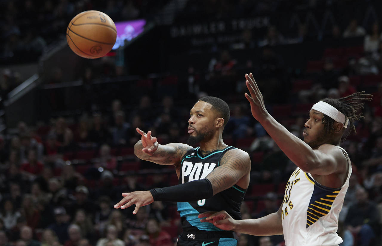 Portland Trail Blazers guard Damian Lillard, left, passes the ball away from Indiana Pacers center ...
