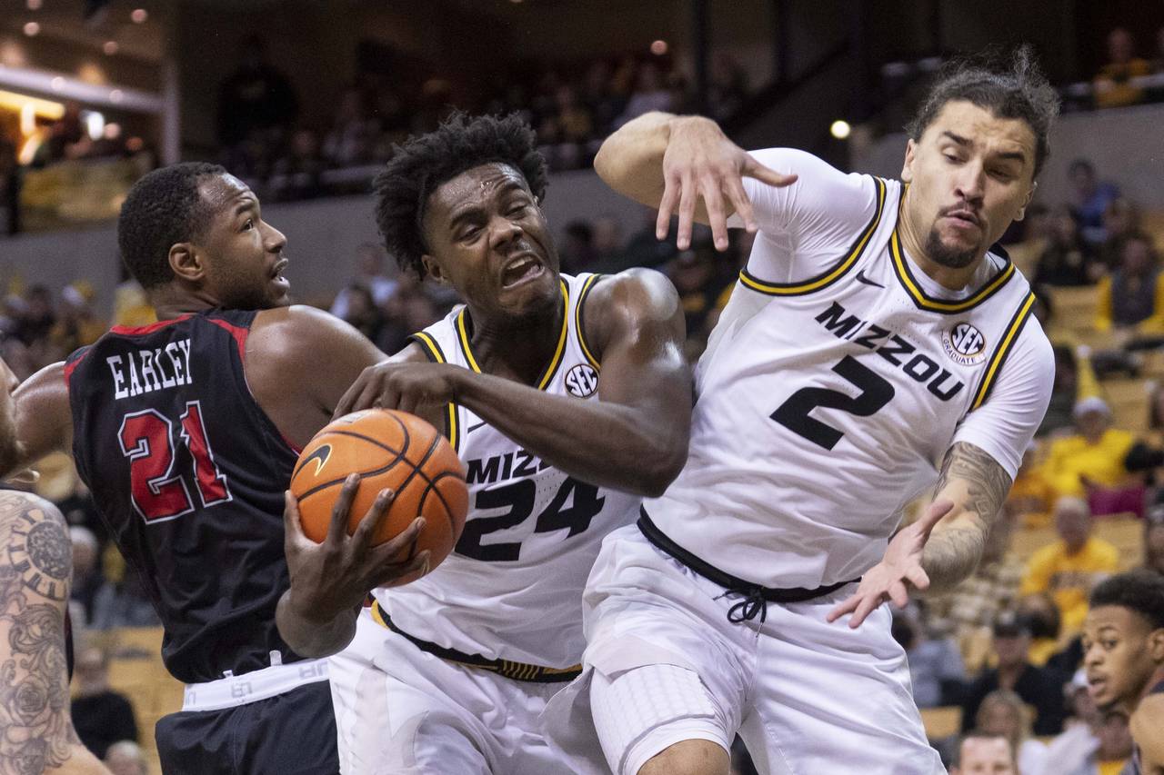 Missouri's Kobe Brown, center, pulls down a rebound between teammate Tre Gomillion, right, and Sout...