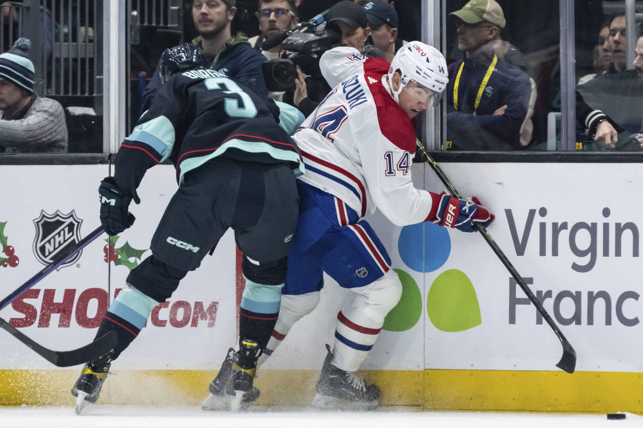 Seattle Kraken defenseman Will Borgen, left, checks Montreal Canadiens forward Nick Suzuki against ...