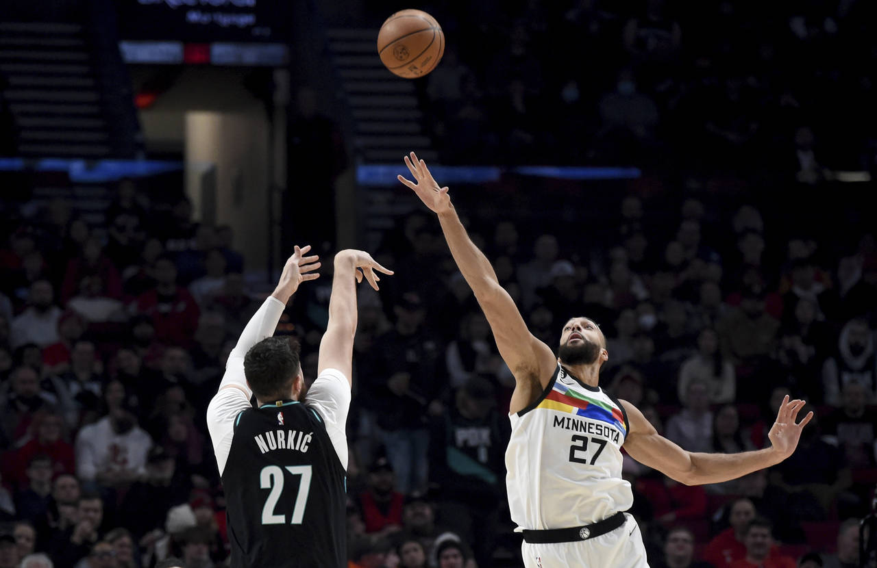 Portland Trail Blazers center Jusuf Nurkic, left, hits a shot over Minnesota Timberwolves center Ru...