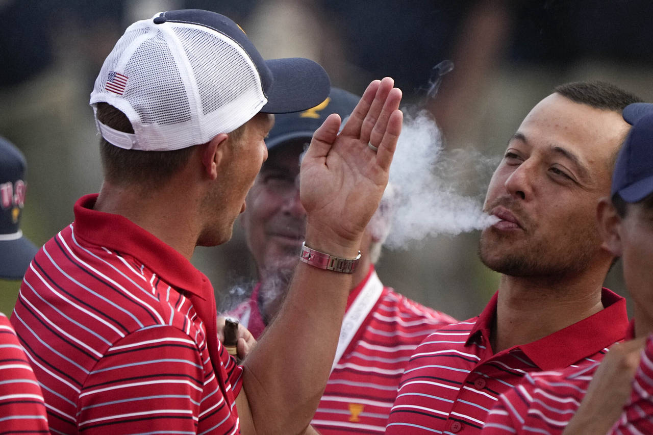 FILE - Xander Schauffele blows smoke toward Jordan Spieth after the USA team defeated the Internati...