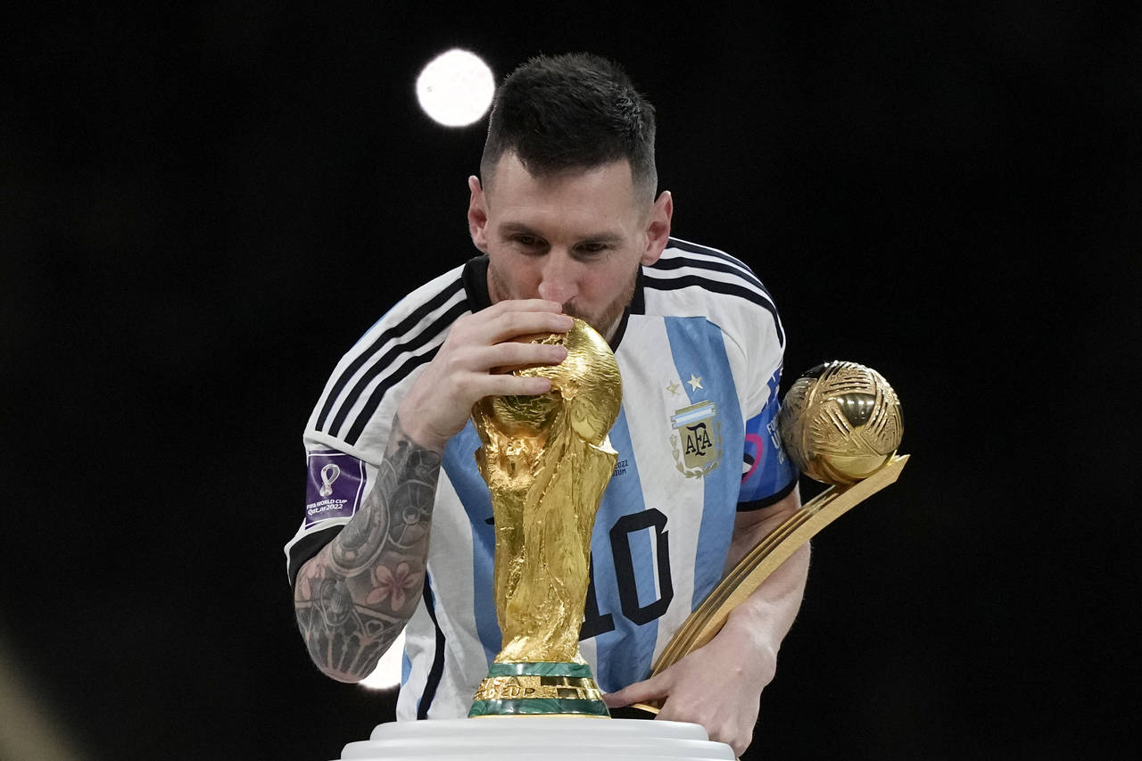 Argentina's Lionel Messi kisses the trophy after winning the World Cup final soccer match between A...