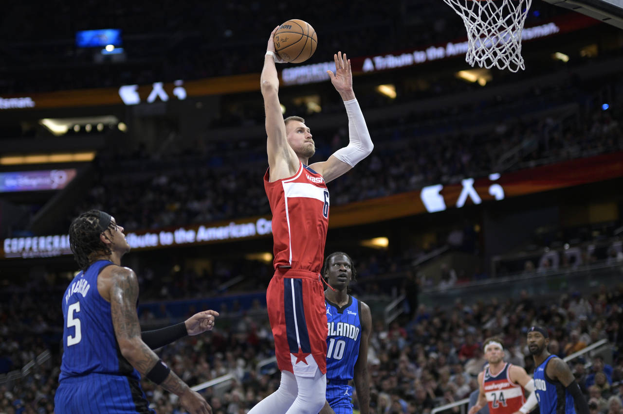 Washington Wizards center Kristaps Porzingis (6) goes up for a dunk between Orlando Magic forward P...