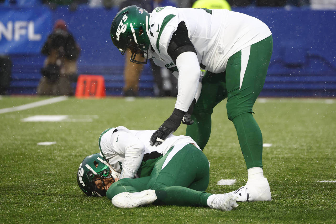 New York Jets offensive tackle Duane Brown, top, checks on quarterback Mike White, below, in the fi...