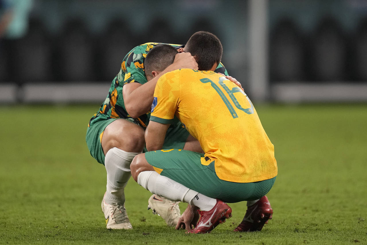 Australia's Aziz Behich is comforted after losing the World Cup round of 16 soccer match between Ar...
