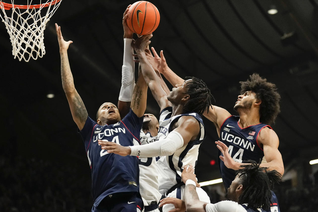 Connecticut's Jordan Hawkins, left, and Andre Jackson Jr., right, battle for a rebound with Butler ...