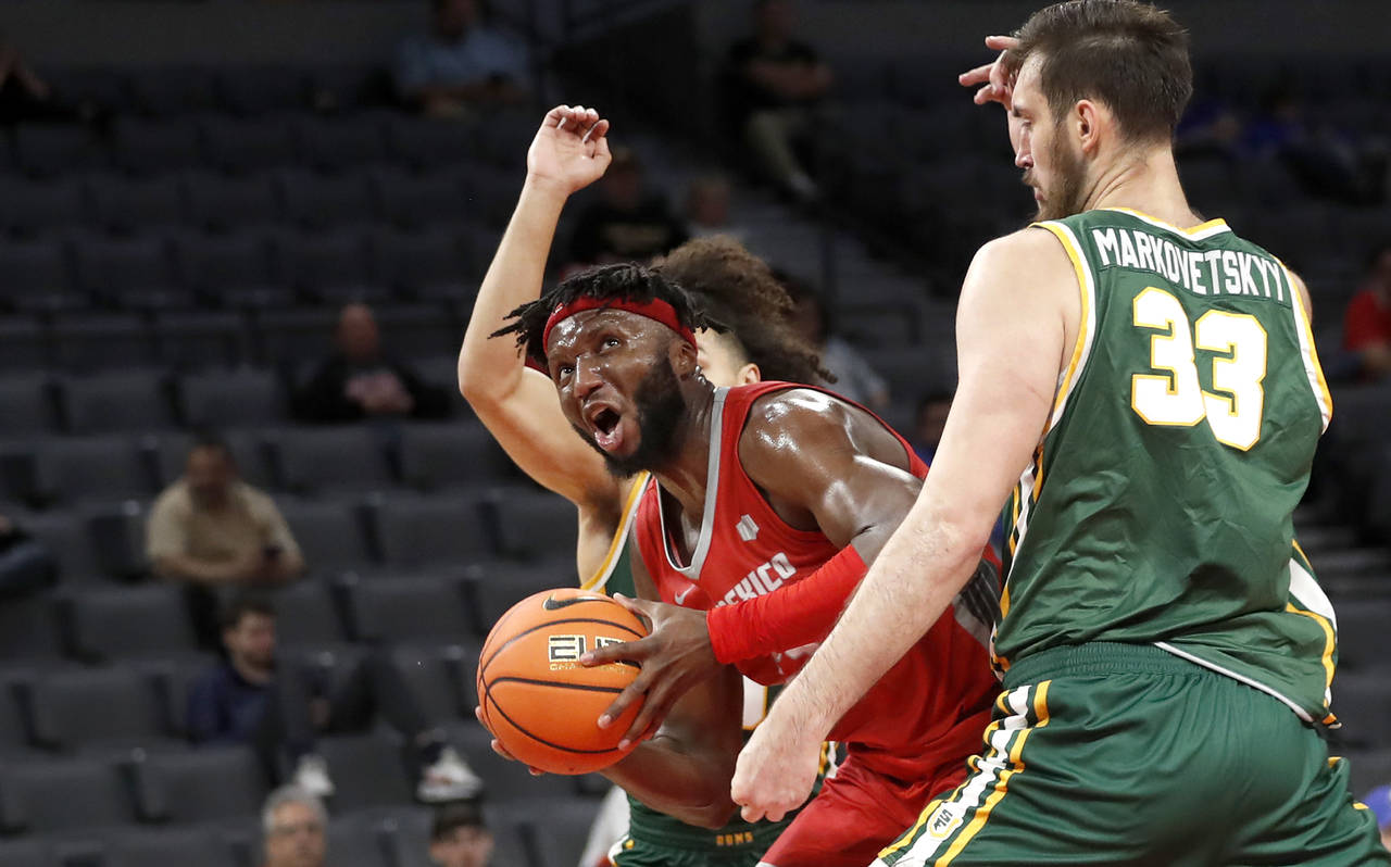 New Mexico forward Morris Udeze (24) drives past San Francisco center Volodymyr Markovetskyy (33) d...
