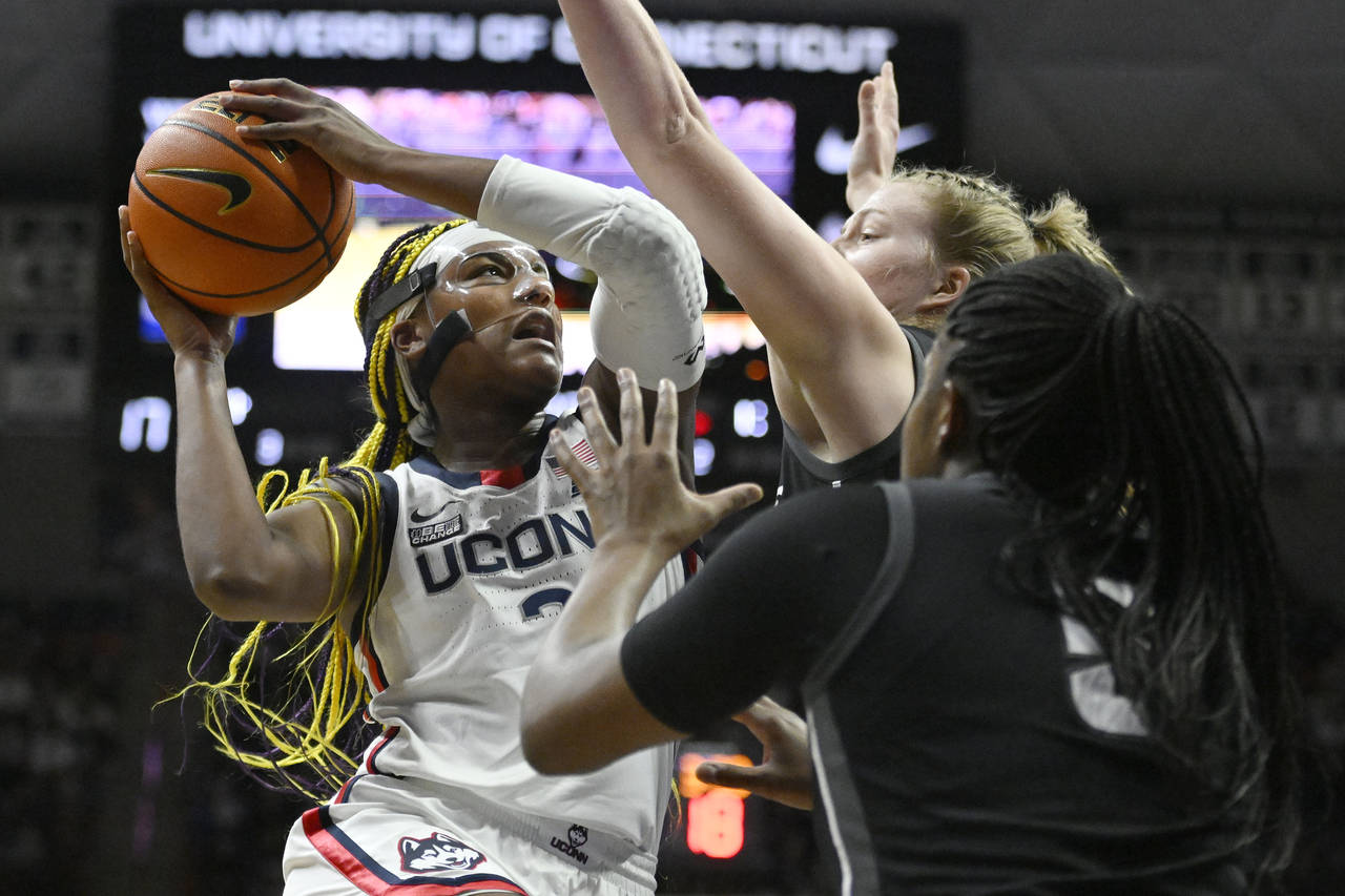 Connecticut's Aaliyah Edwards, left, goes up for a basket as Providence's Emily Archibald, center, ...