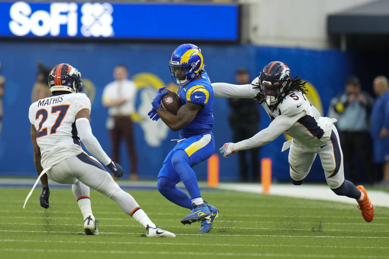 Los Angeles Rams running back Cam Akers runs between Denver Broncos cornerback Damarri Mathis, left...