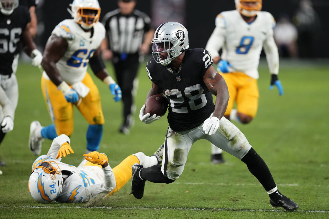 Las Vegas Raiders running back Josh Jacobs (28) carries past Los Angeles Chargers safety Nasir Adde...