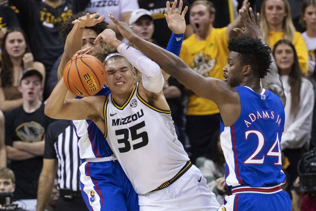 Missouri's Noah Carter, center, fights his way between Kansas' K.J. Adams Jr., right, and Jalen Wil...