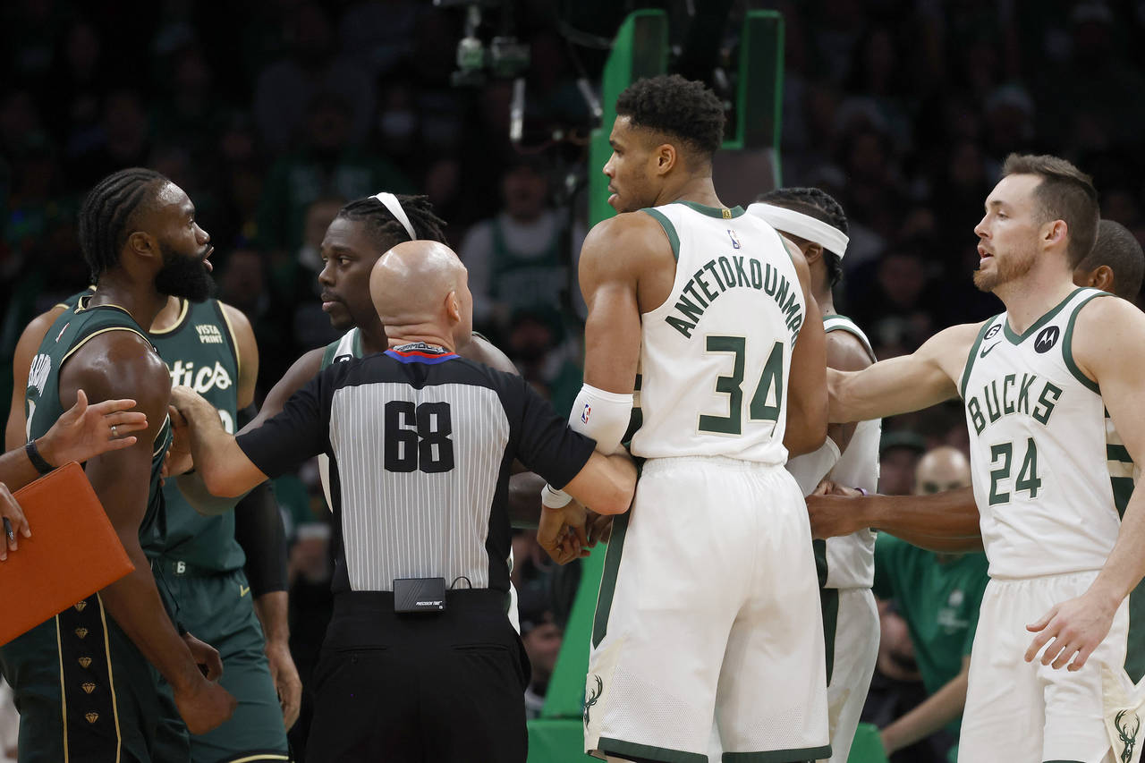 Referee Jacyn Goble (68) steps between Boston Celtics guard Jaylen Brown, left, and Milwaukee Bucks...
