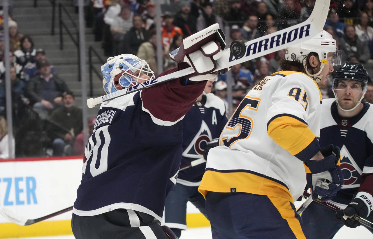 Colorado Avalanche goaltender Alexandar Georgiev, left, makes a stick-save of a shot while hitting ...