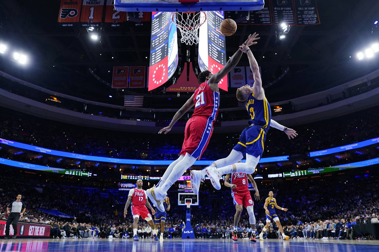 Golden State Warriors' Donte DiVincenzo, right, tries to get a shot past Philadelphia 76ers' Joel E...