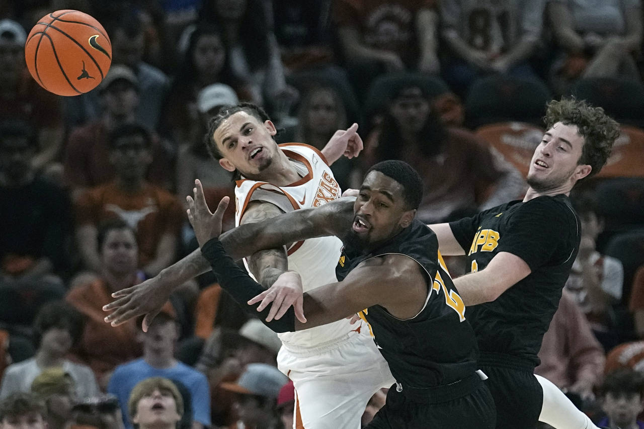 Texas forward Christian Bishop, left, and Arkansas-Pine Bluff guard Shaun Doss Jr., center, battle ...