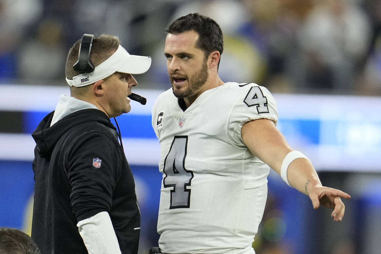 Las Vegas Raiders head coach Josh McDaniels, left, talks with quarterback Derek Carr during the sec...