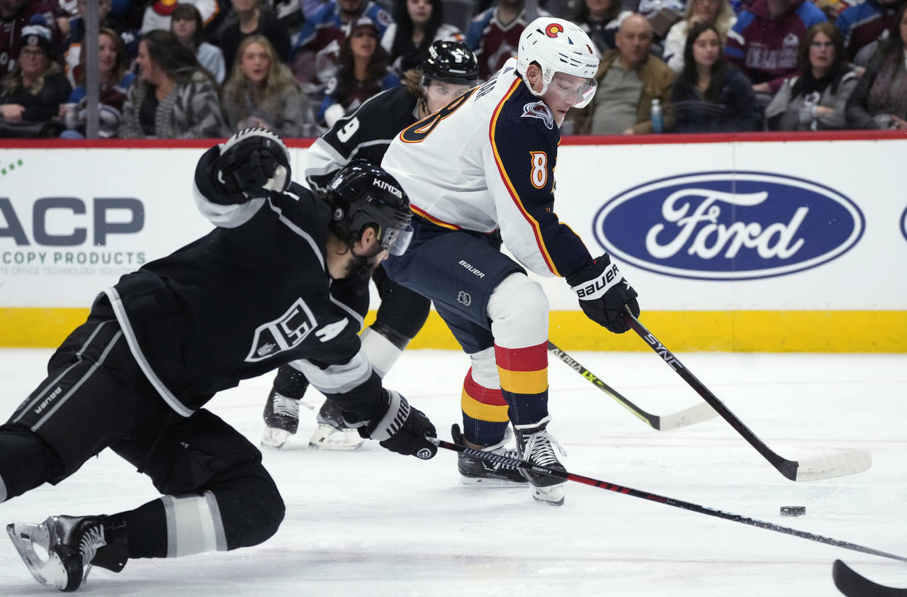 Colorado Avalanche defenseman Cale Makar, center, drives between Los Angeles Kings defenseman Drew ...