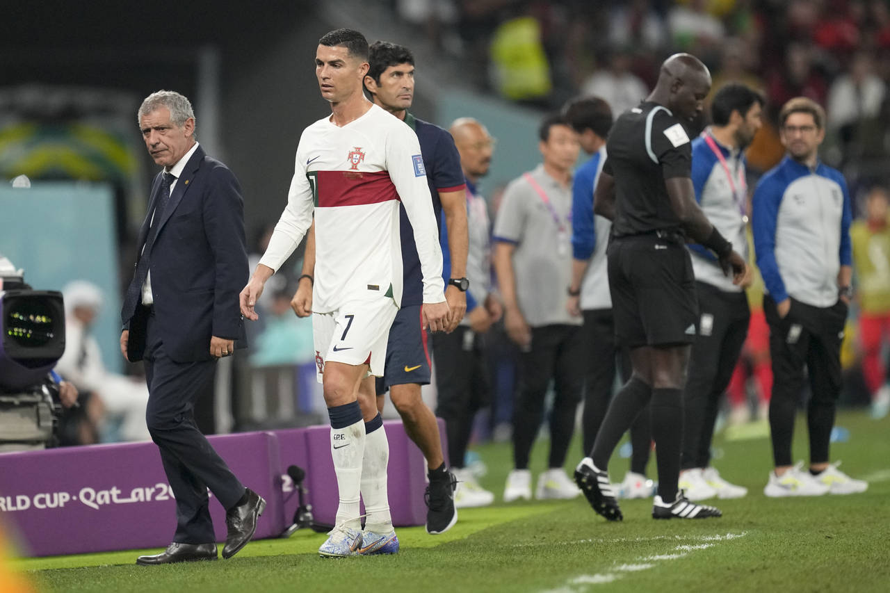 Portugal's Cristiano Ronaldo, center, passes beside his coach Fernando Santos as he leaves the fiel...