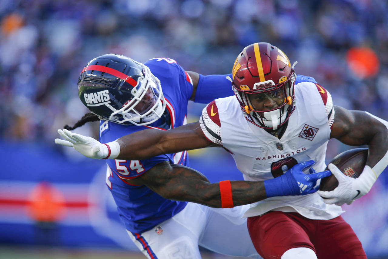 Washington Commanders' Brian Robinson Jr., right, runs past New York Giants' Jaylon Smith during th...