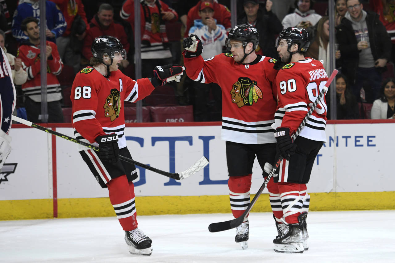Chicago Blackhawks' Max Domi (13) celebrates with Patrick Kane (88) and Tyler Johnson (90) after sc...