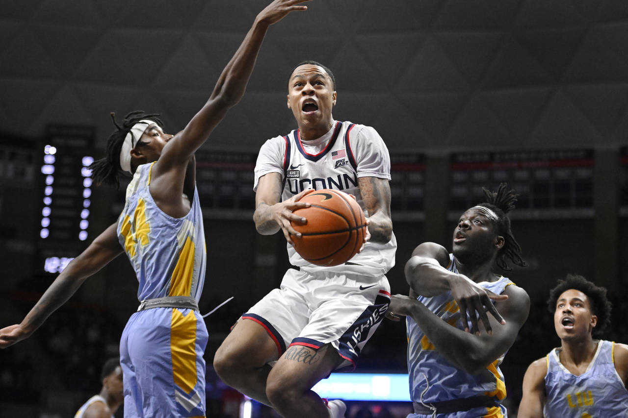 Connecticut's Jordan Hawkins, center, goes up for a basket as Long Island's Quion Burns, left, and ...