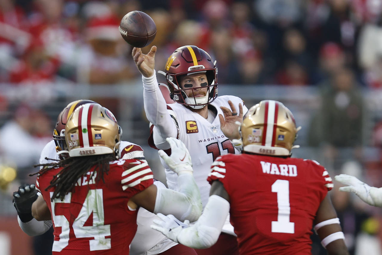 Washington Commanders quarterback Carson Wentz throws a pass as he is pressured by San Francisco 49...