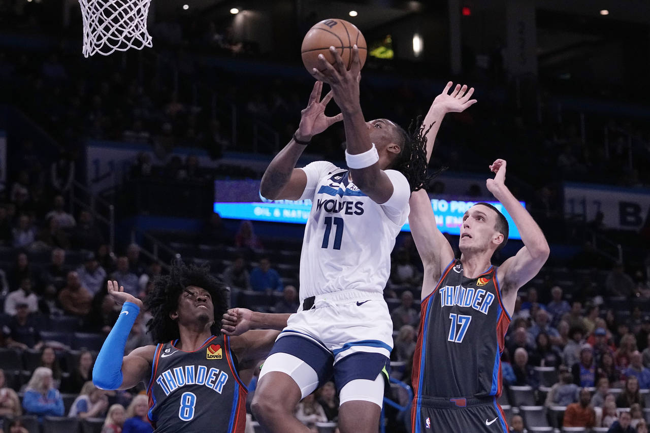 Minnesota Timberwolves center Naz Reid (11) goes to the basket between Oklahoma City Thunder forwar...