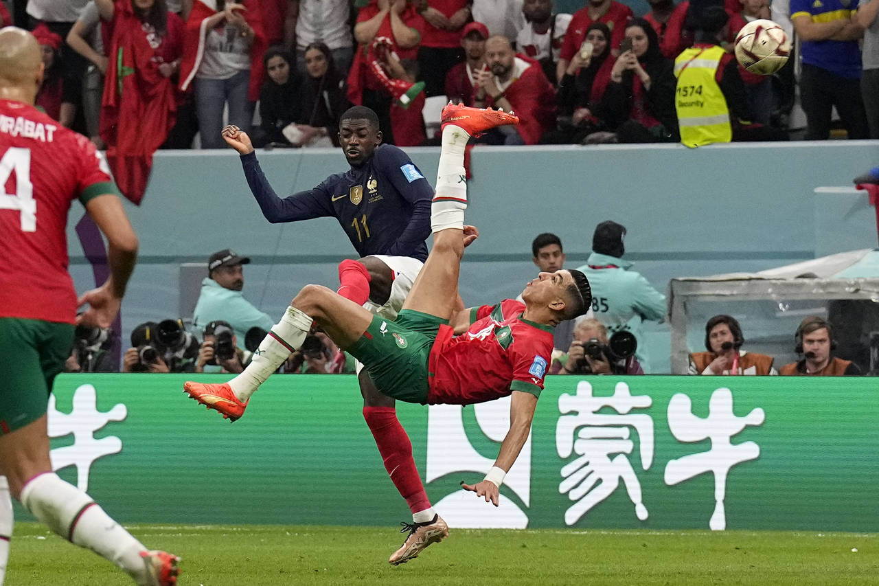 Morocco's Jawad El Yamiq attempts a shot at goal as France's Ousmane Dembele during the World Cup s...