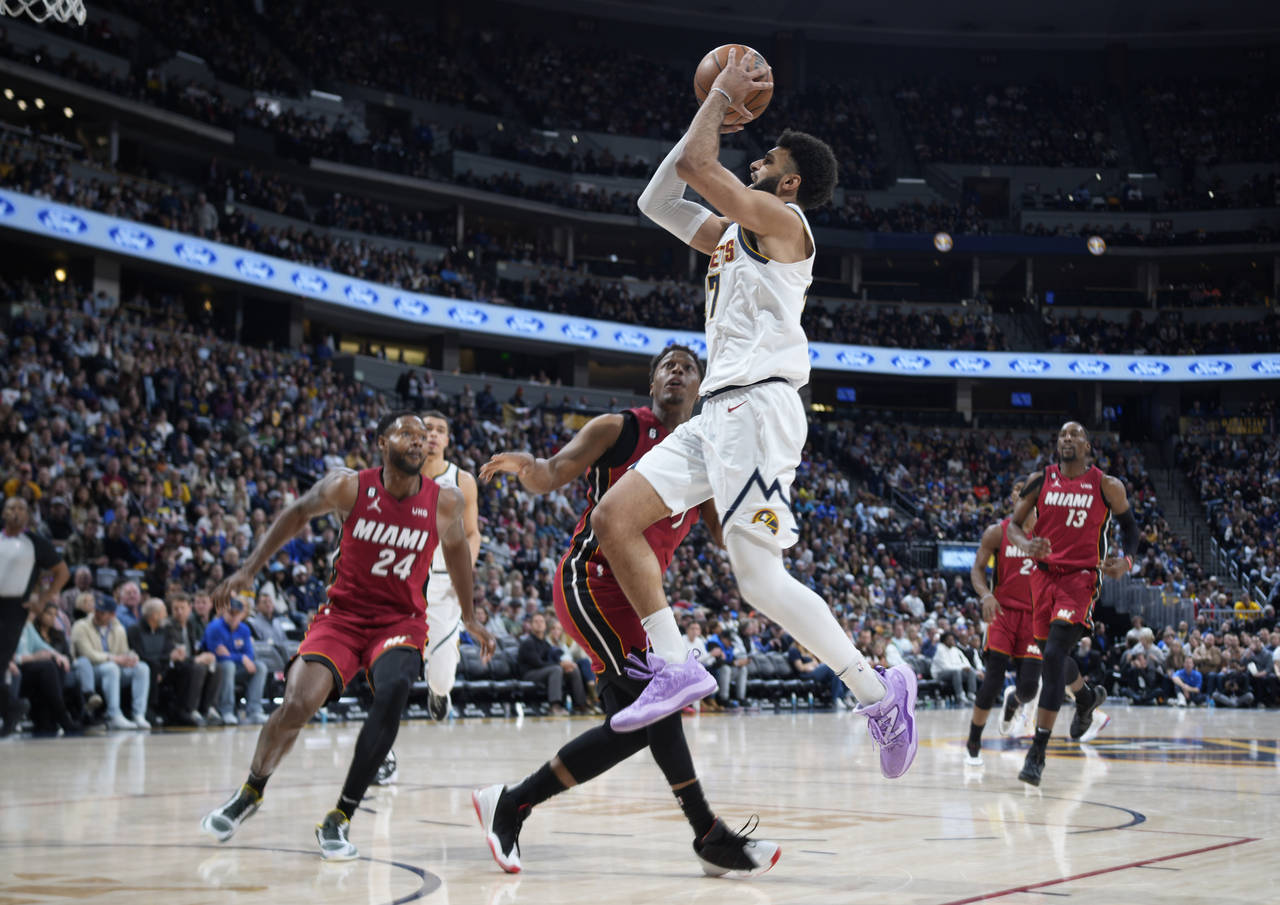 Denver Nuggets guard Jamal Murray, top center, goes up for a basket as Miami Heat forward Haywood H...