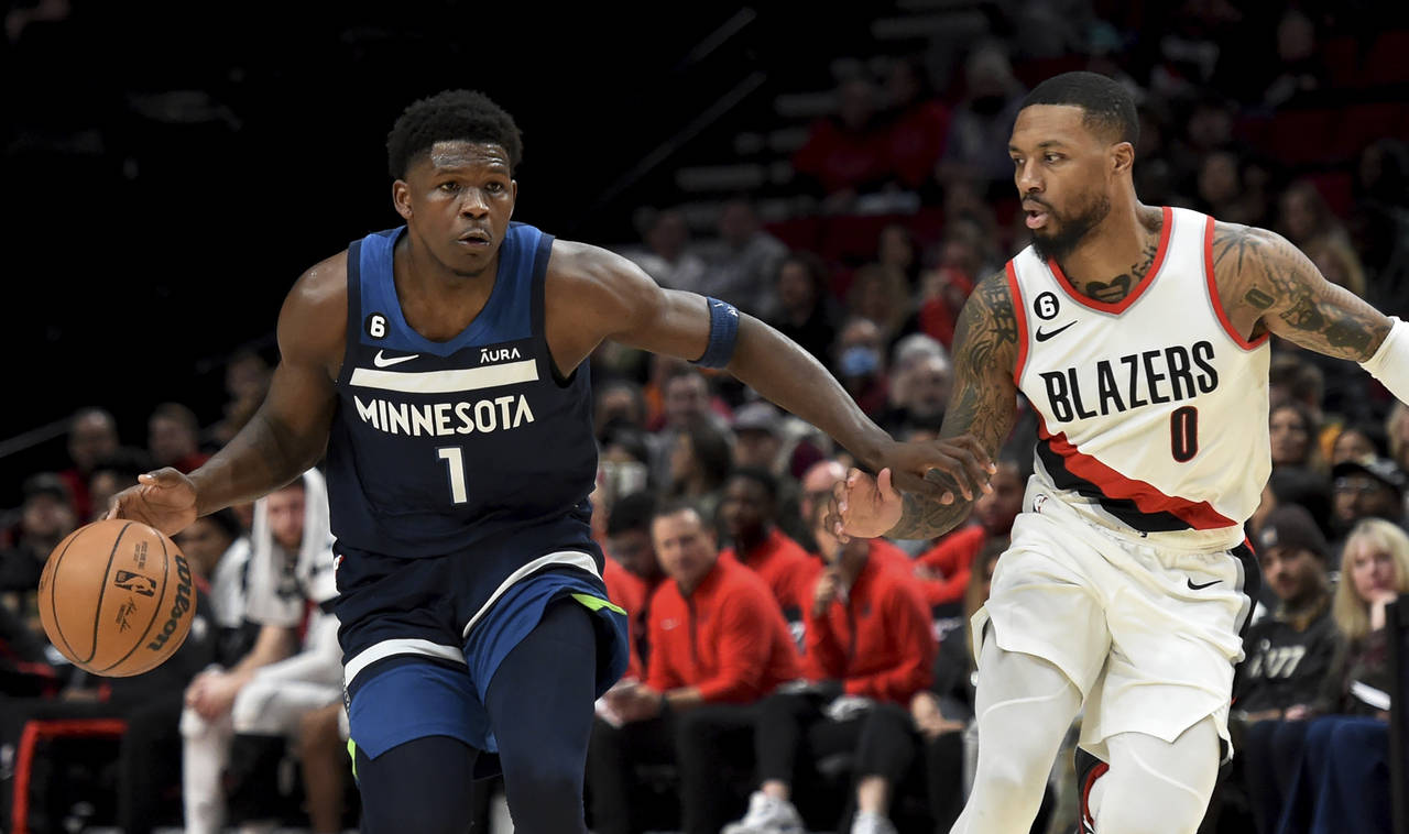 Minnesota Timberwolves guard Anthony Edwards, left, brings the ball up the court on Portland Trail ...