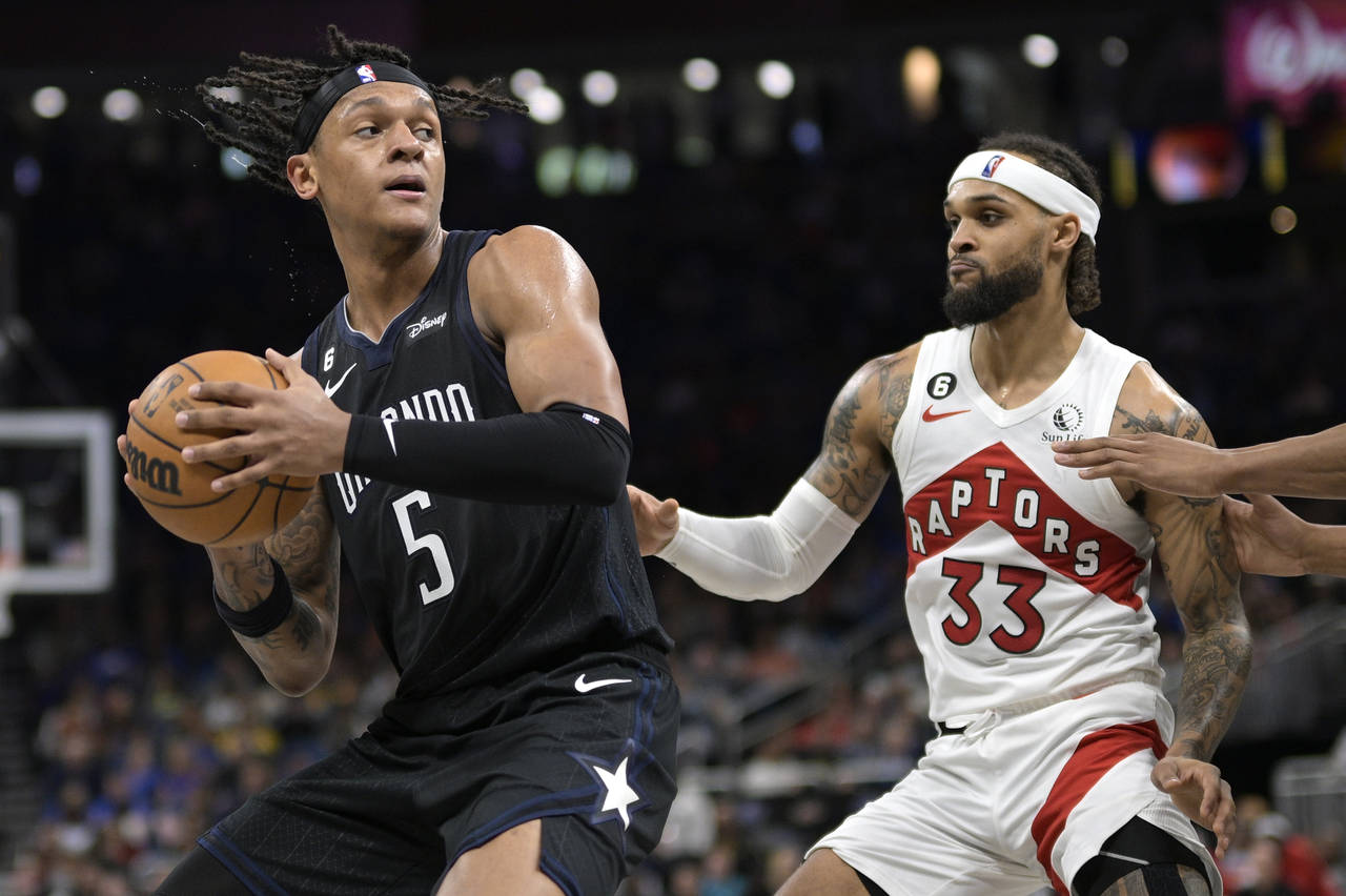 Orlando Magic forward Paolo Banchero (5) is defended by Toronto Raptors guard Gary Trent Jr. (33) d...