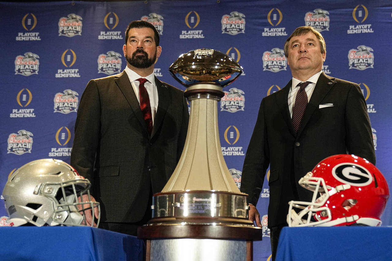 Ohio State head coach Ryan Day, left and Georgia head coach Kirby Smart stand with the trophy durin...