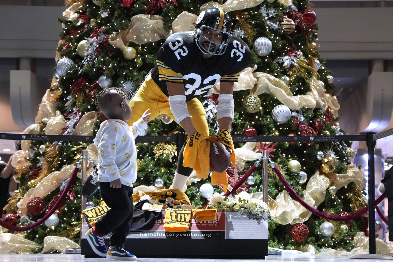 Three-year-old Steven Wooten, of Atlanta, looks at a statue depicting the "Immaculate Reception" by...