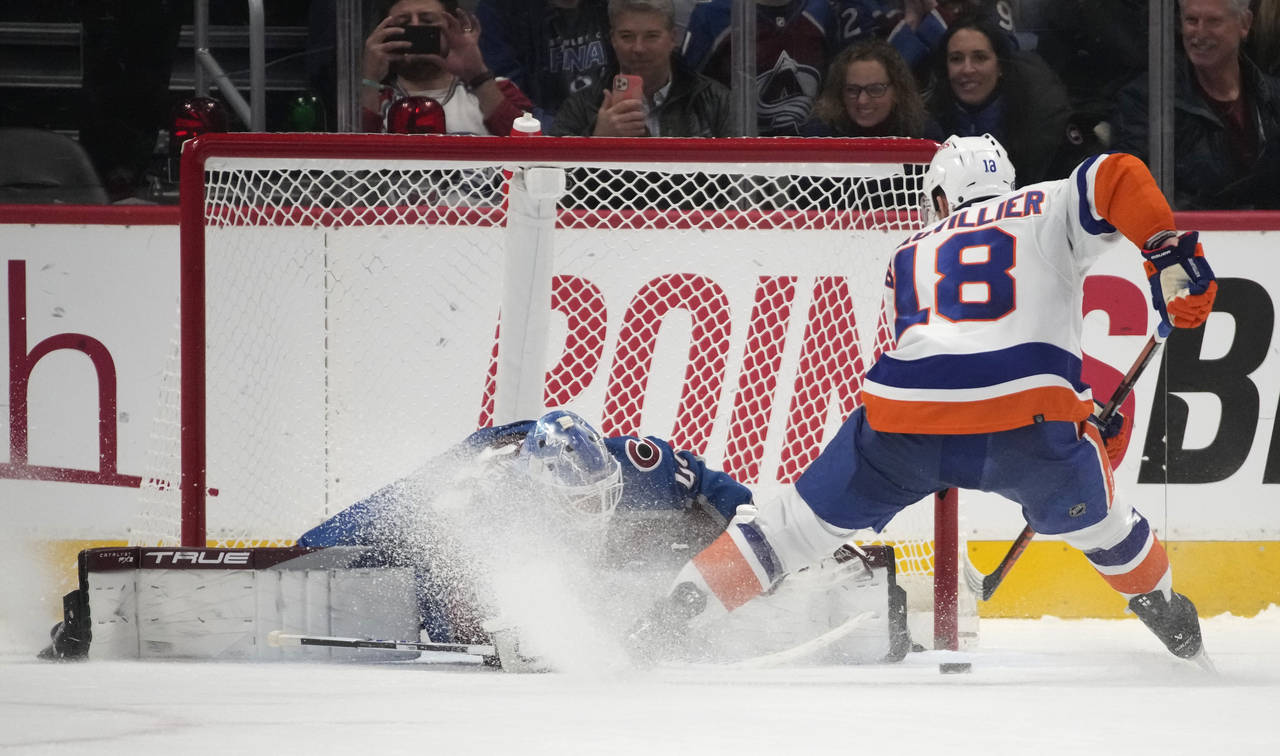 Colorado Avalanche goaltender Alexandar Georgiev, left, stops a shot off the stick of New York Isla...
