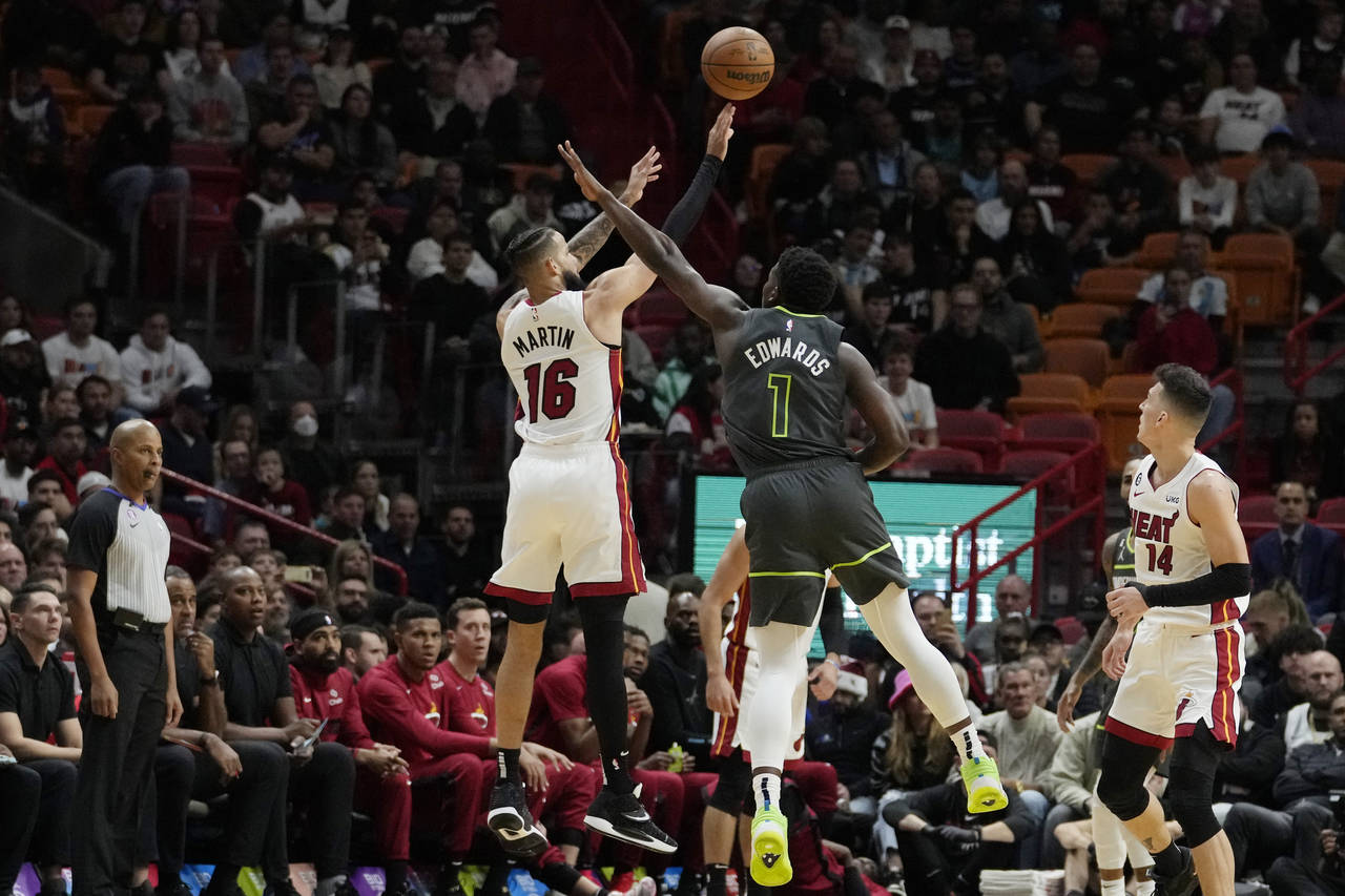 Miami Heat forward Caleb Martin (16) shoots as Minnesota Timberwolves guard Anthony Edwards (1) def...