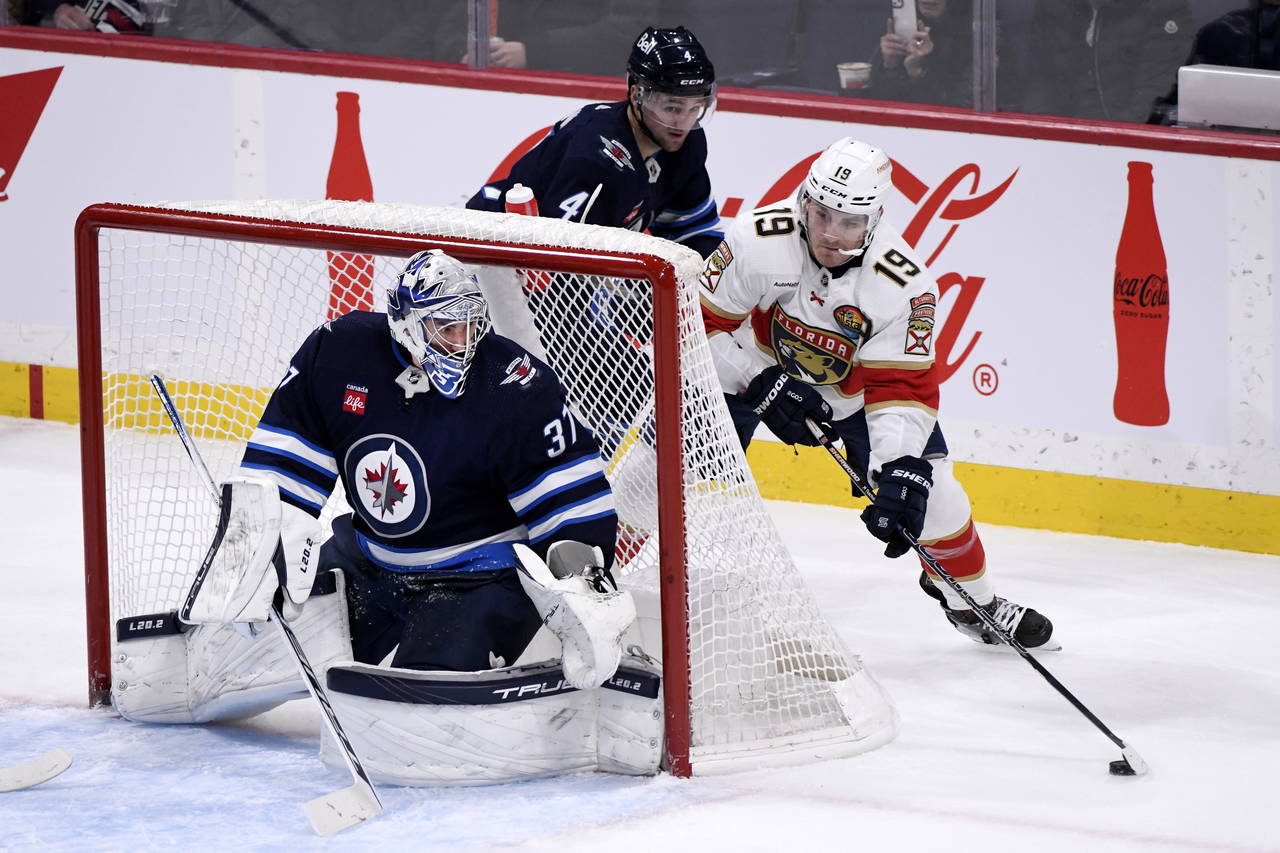 Florida Panthers' Matthew Tkachuk (19) carries the puck behind Winnipeg Jets goaltender Connor Hell...
