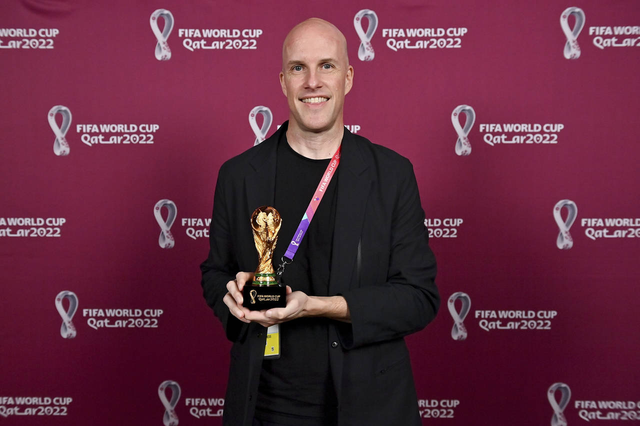 Grant Wahl smiles as he holds a World Cup replica trophy during an award ceremony in Doha, Qatar on...