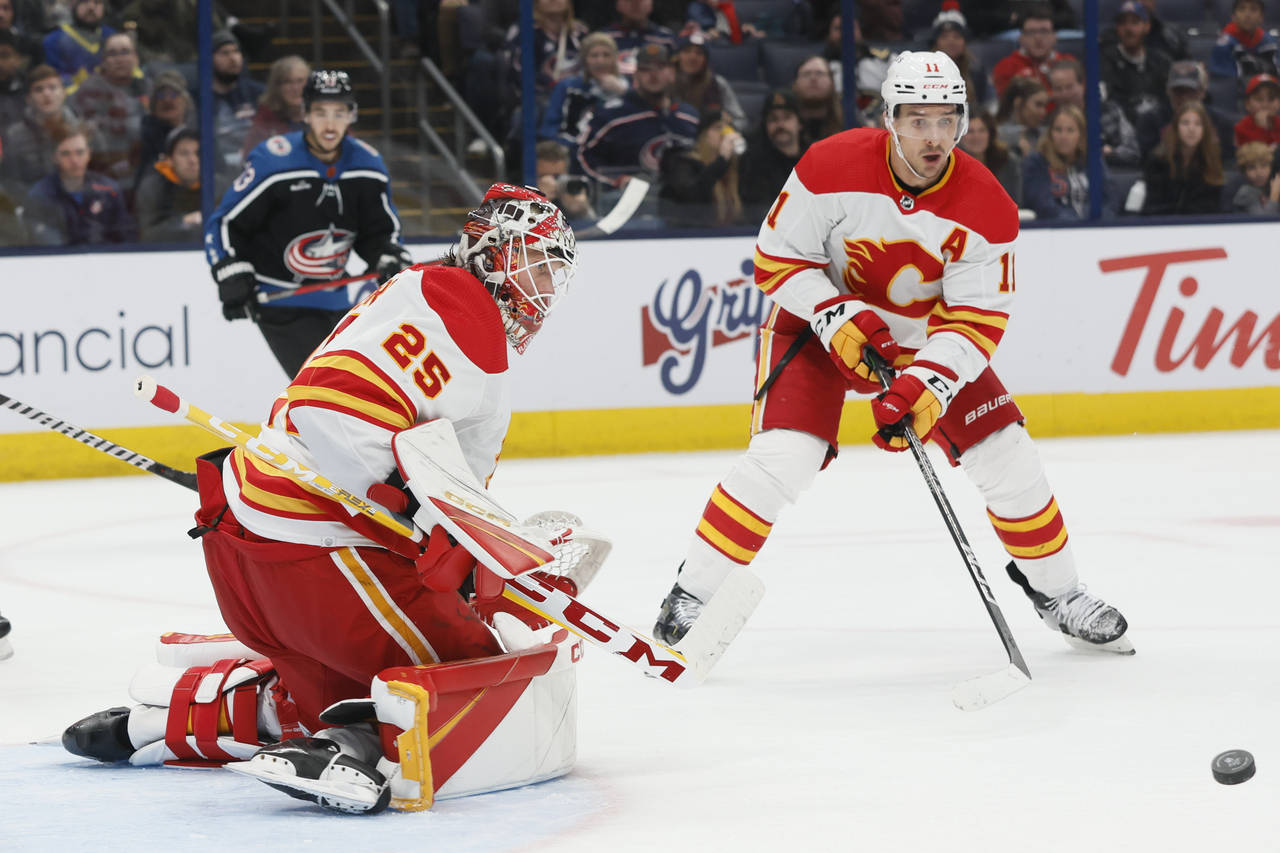 Calgary Flames' Jacob Markstrom, left, makes a save against the Columbus Blue Jackets during the se...