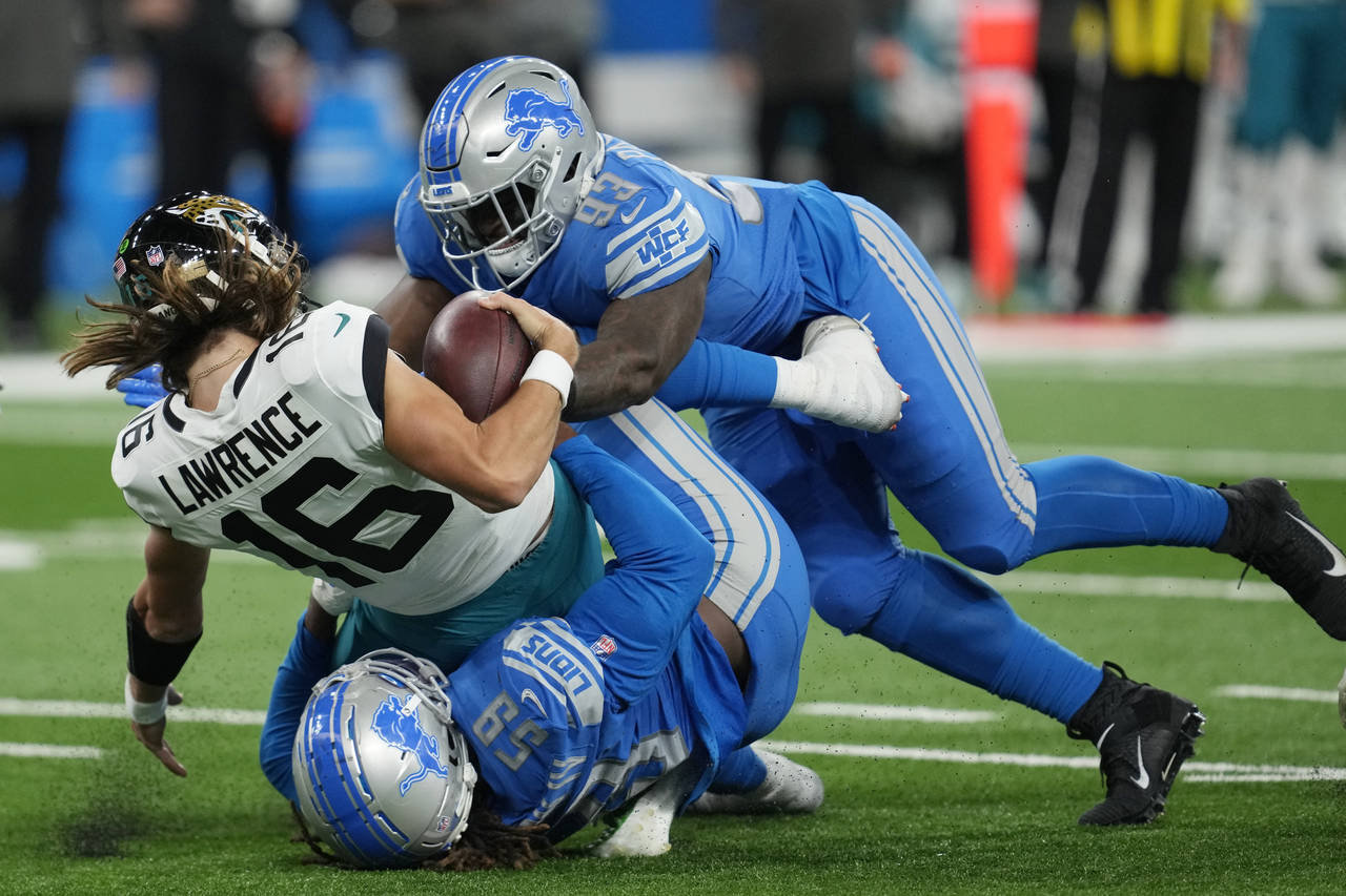 Jacksonville Jaguars quarterback Trevor Lawrence (16) is sacked by Detroit Lions linebacker James H...