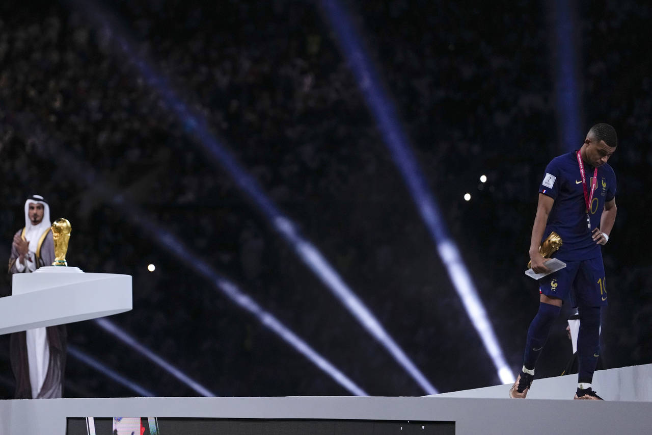 France's Kylian Mbappe walks past the trophy at the end of the World Cup final soccer match between...