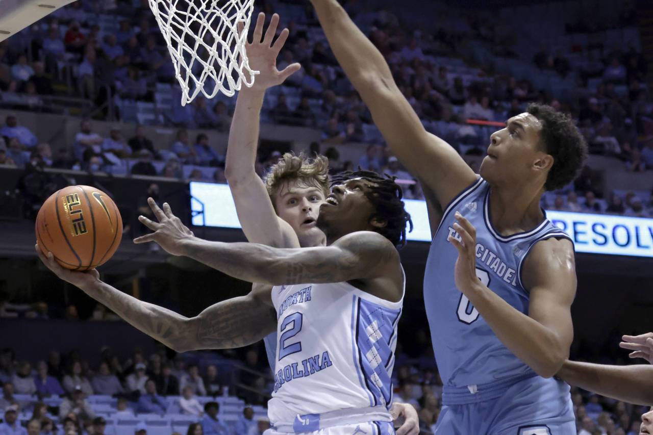 North Carolina guard Caleb Love (2) drives in against Citadel forwards Stephen Clark (1) and forwar...