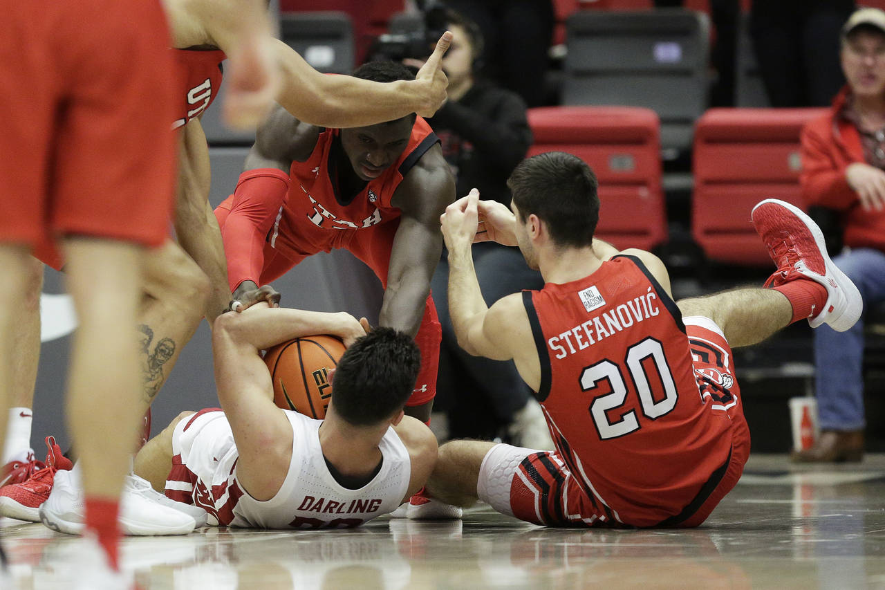 Utah center Keba Keita, top, guard Lazar Stefanovic, right, and Washington State guard Dylan Darlin...