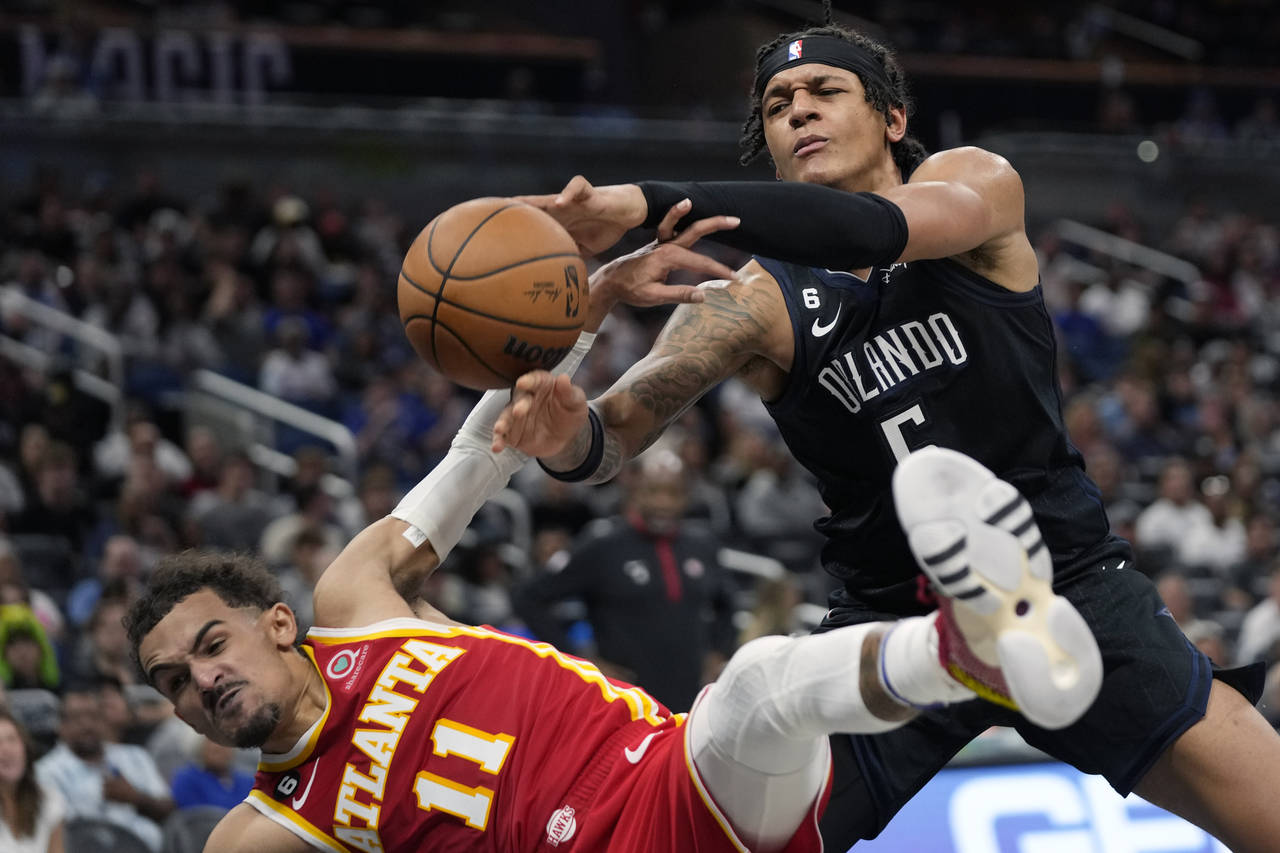 Atlanta Hawks' Trae Young, left, fouls Orlando Magic's Paolo Banchero (5) as he goes in for a shot ...