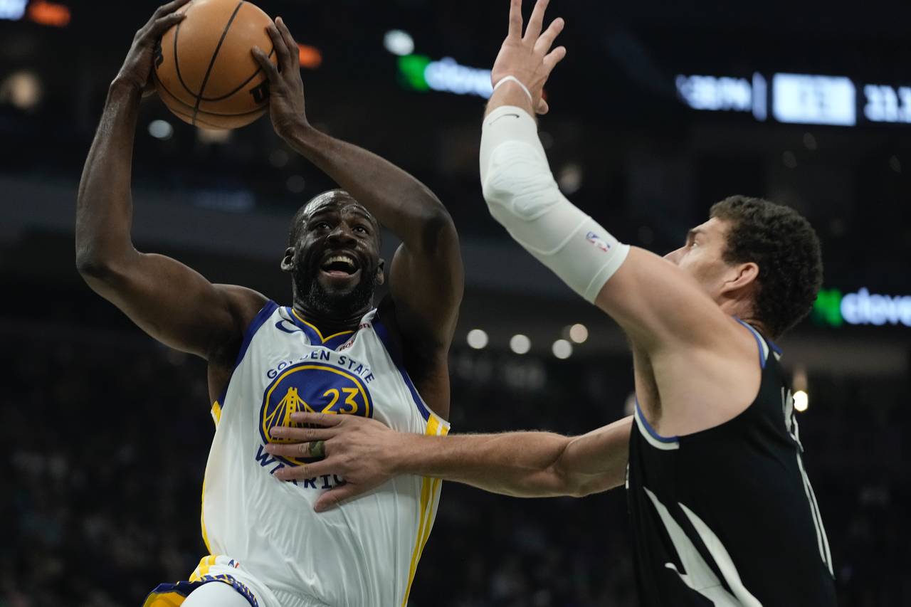 Golden State Warriors' Draymond Green shoots past Milwaukee Bucks' Brook Lopez during the first hal...