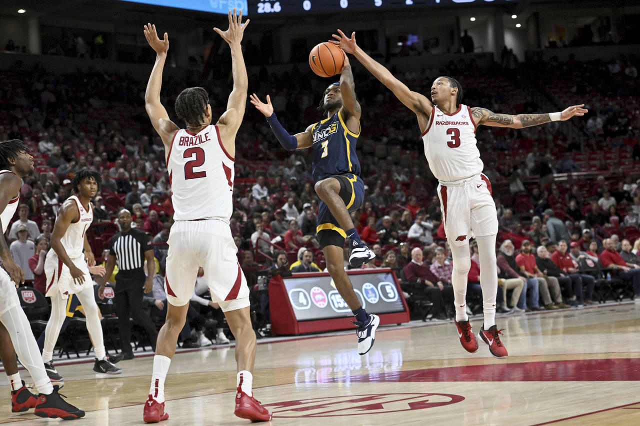 UNC Greensboro guard Kobe Langley (3) tries to drive past Arkansas defenders Trevon Brazile (2) and...