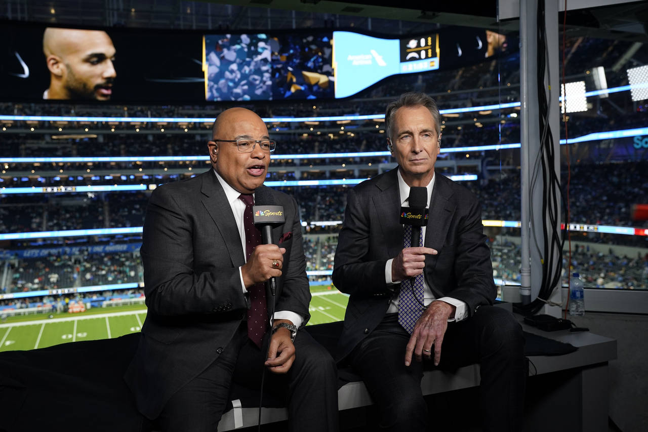 NBC Sports play-by-play announcer Mike Tirico, left, sits next to color commentator Cris Collinswor...