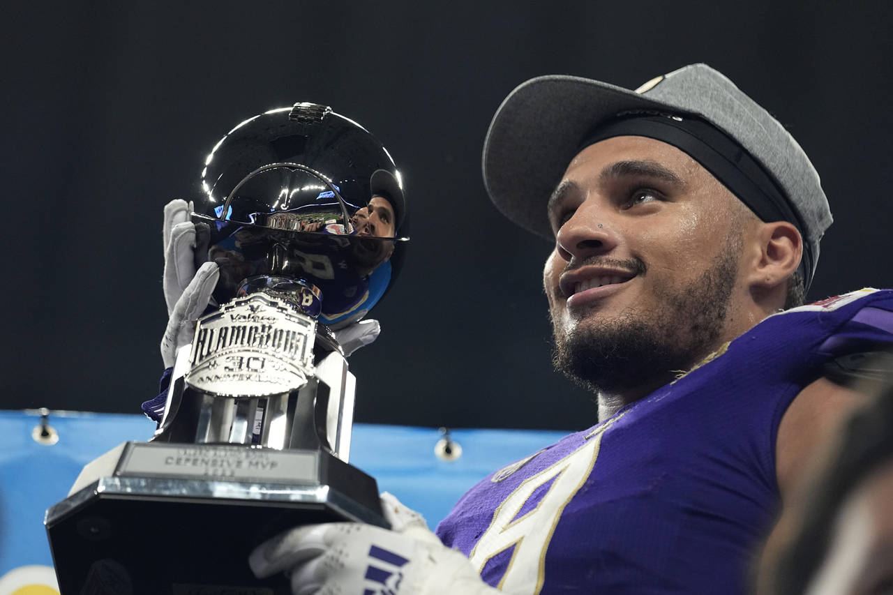 Washington defensive lineman Bralen Trice holds his Defensive MVP trophy after defeating Texas in t...